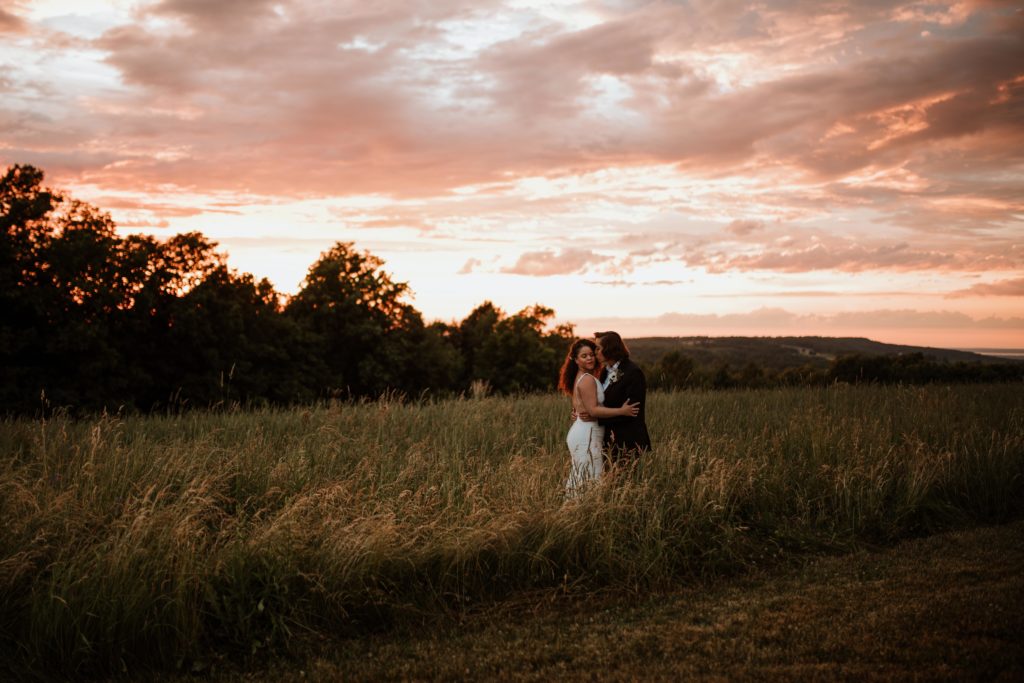 Newlywed couple at sunset in a field.