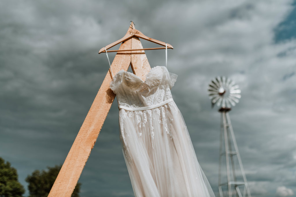 Wedding dress hanging from arbor with a windmill in the background.