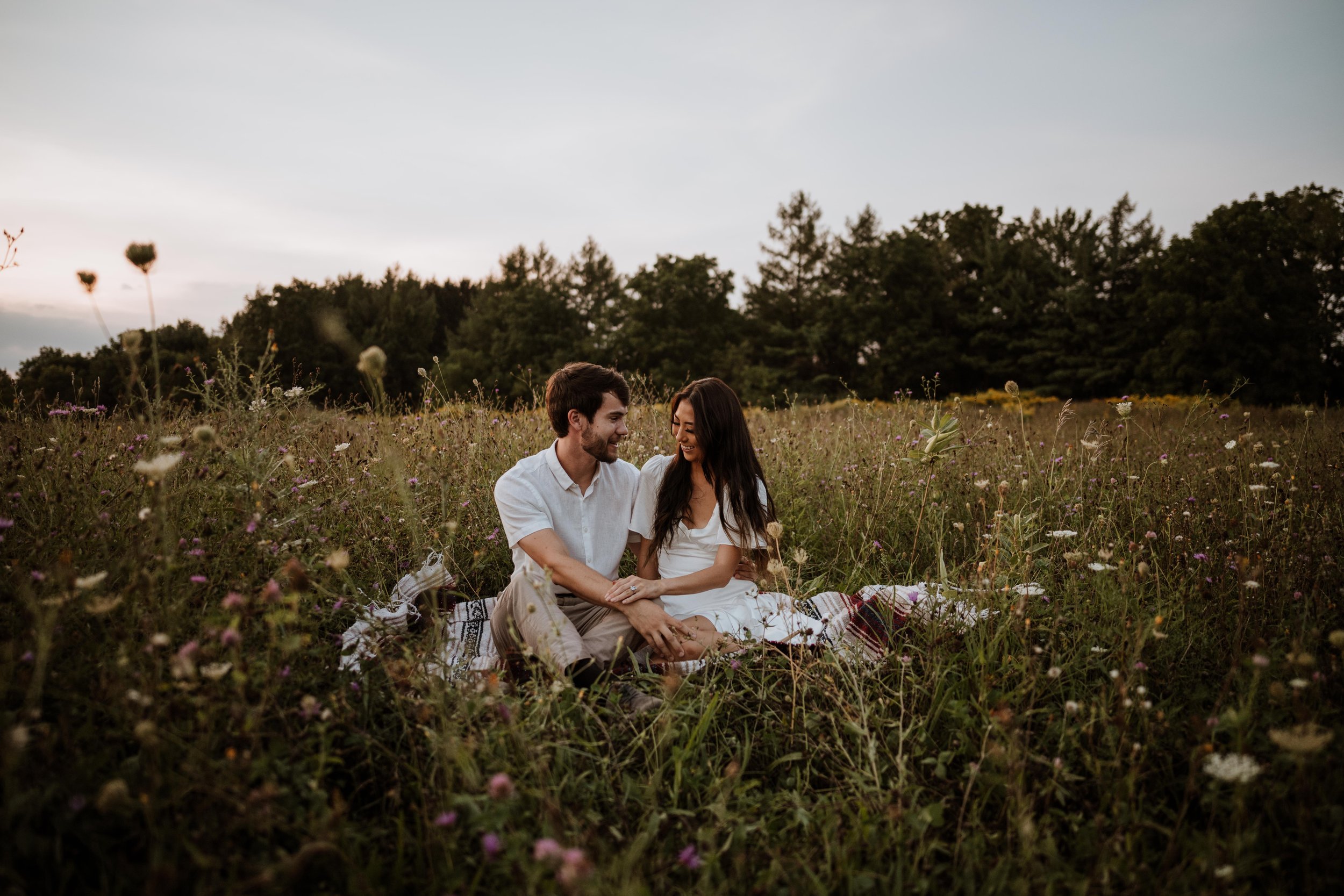 A couple enjoying the sunset together in a field of wildflowers.